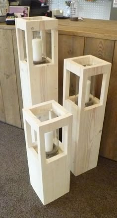 three wooden containers with candles in them sitting on the floor next to a counter top