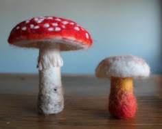 two mushrooms sitting on top of a wooden table next to each other, one red and the other white