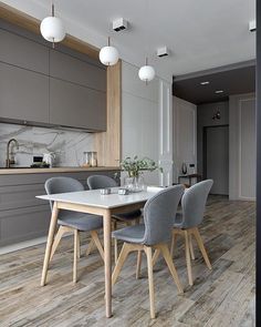 a dining room table and chairs in front of an open kitchen area with gray cabinets