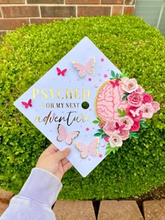 someone is holding up a graduation cap with flowers and butterflies on it that says, psychic for my next adventure