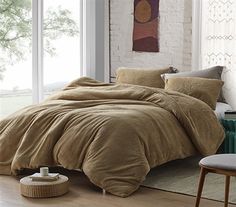 a bedroom with a large bed covered in brown comforter and two chairs next to it