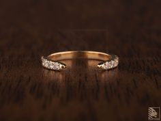 a gold ring with three diamonds on a wooden surface