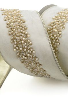 a white pillow with gold trim and pearls on it