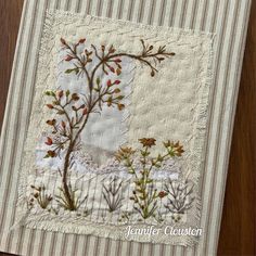 a close up of a piece of cloth on a wooden table with flowers and leaves