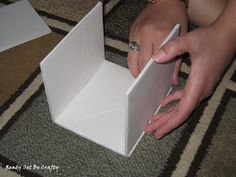 a woman is opening an empty box on the floor with her hand and ring in it