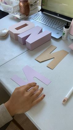 someone is making letters out of cardboard on a table next to a laptop and mouse