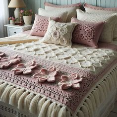 a bed with pink and white crocheted bedspread, pillows and blankets