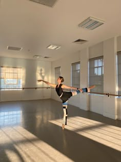 a woman is practicing ballet in an empty room with sunlight streaming through the windows and casting shadows on the floor