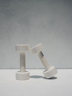 two white objects sitting on top of each other in front of a gray wall and floor