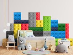 a room with lego blocks on the wall and stuffed animals in front of the bed