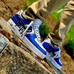 a person standing on top of a rock with their feet in the air and wearing blue sneakers