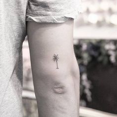 a small palm tree tattoo on the left arm