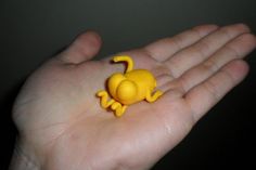 a small yellow toy animal sitting on someone's palm