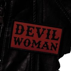 the devil woman patch is attached to a black leather jacket with red lettering on it