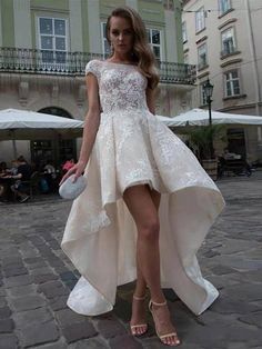 a woman in a white dress is standing on a brick road with her legs spread out