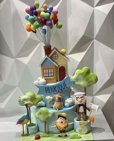 a cake that has some balloons in the shape of houses and animals on top of it