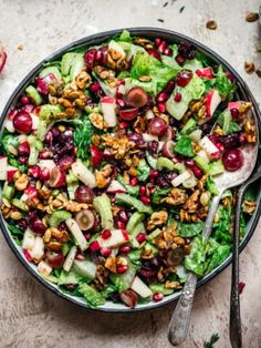 a salad with apples, walnuts and cranberries in a bowl on a table