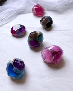 five different colored glass beads on a white surface