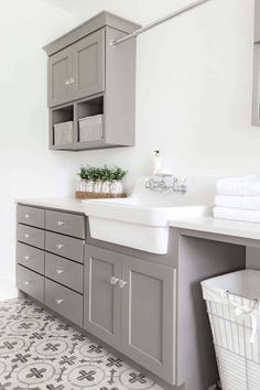 a bathroom with gray cabinets and white sink in the center, next to a laundry basket