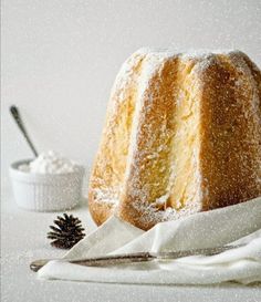 a bundt cake with powdered sugar and a pine cone on the napkin next to it