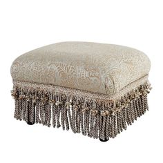 a large ottoman with tassels and fringe trim on the bottom, sitting in front of a white background