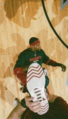 a man sitting on top of a basketball court holding a shoe