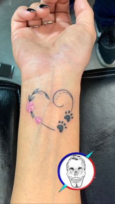 a person with a tattoo on their wrist holding up a dog's paw and heart