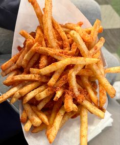 a pile of french fries sitting on top of a white paper plate covered in seasoning