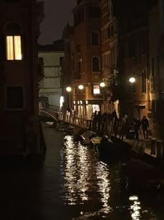 people are standing on the side of a canal at night