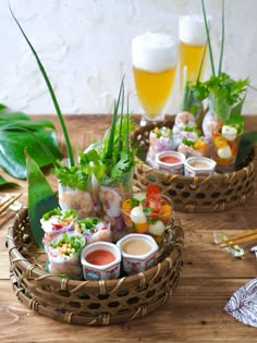 two baskets filled with food sitting on top of a wooden table next to beer glasses