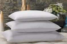 three pillows stacked on top of each other in front of a brick wall and vase