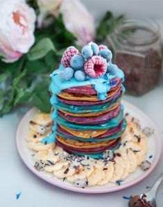 a stack of pancakes covered in blue frosting and berries on top of each other