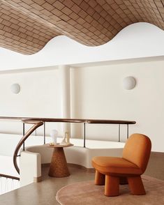 an orange chair sitting in the middle of a room next to a table and stairs