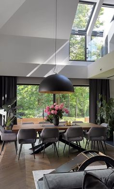 a dining room table with chairs and a large window in the back ground floor to ceiling windows