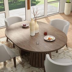 a dining room table with white chairs and plates on the table in front of large windows