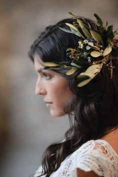 a woman wearing a flower crown with leaves on her head and hair in the wind