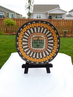 a decorative plate sitting on top of a white table in front of a wooden fence