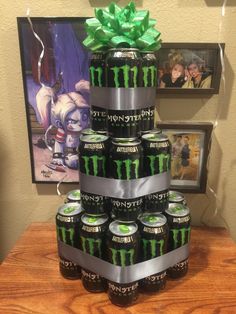 a stack of monster energy cans on top of a wooden table with a green bow