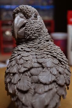 a bird statue sitting on top of a wooden table next to a can of soda