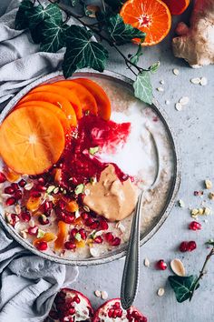 a bowl filled with oatmeal, fruit and nuts next to oranges