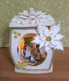 a nativity scene in a white box with snowflakes on the top and two people inside