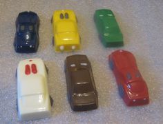 six toy cars are lined up in a row on the floor, all different colors