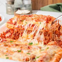 someone is taking a slice of lasagna from the casserole dish