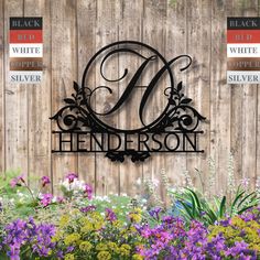 a metal monogrammed sign with flowers in front of a wooden fence