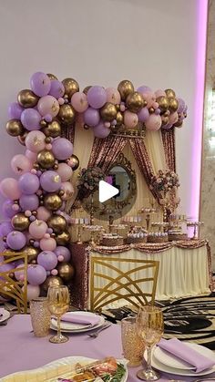 the table is set for a party with purple and gold balloons