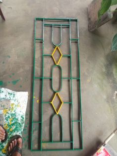 a person standing next to a green and yellow metal rack on the ground with scissors in it