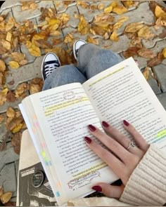 a woman is reading a book in the fall leaves