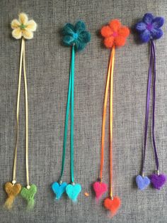 four necklaces with flowers and hearts on them are lined up against a gray background