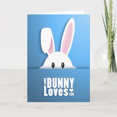 the bunny loves you card is next to a vase with yellow flowers and a blue background