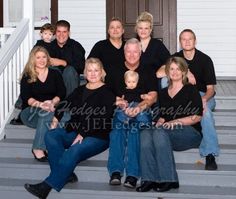 a group of people sitting on steps in front of a house with their arms around each other